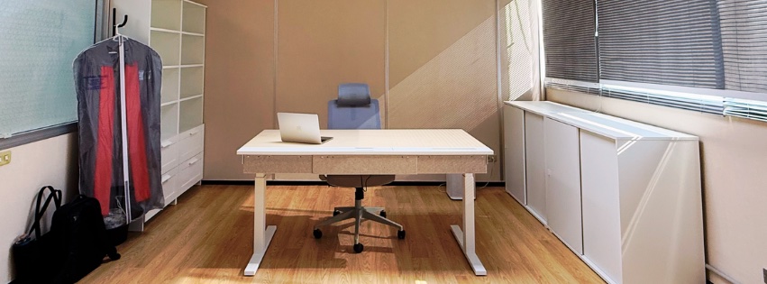 My office: a white standing desk with a laptop and an office chair, shelves on the left and cabinets beneath the window on the right
